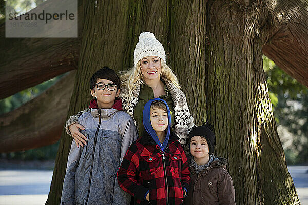 Porträt einer Mutter mit ihren drei Söhnen vor einem großen Baum im Herbst; Langley  British Columbia  Kanada
