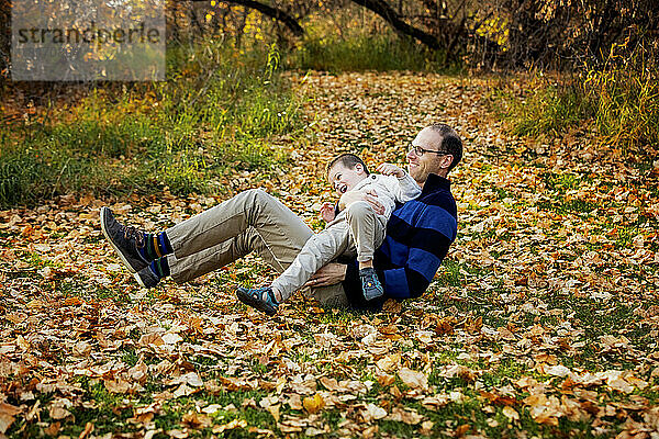 Ein Vater spielt mit seinem Sohn während eines Familienausflugs in einem Stadtpark während der Herbstsaison; St. Albert  Alberta  Kanada