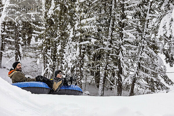 Vater und Sohn beim Tubing auf einem Skihügel; Fairmont Hot Springs  British Columbia  Kanada