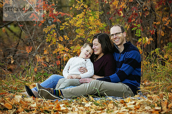 Eine Mutter und ein Vater  die mit ihrem Sohn bei einem Familienausflug in einem Stadtpark während der Herbstsaison einige Zeit verbringen; St. Albert  Alberta  Kanada