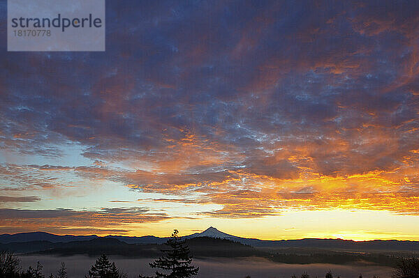 Dramatische glühende Wolken über einem silhouettierten Mount Hood bei Sonnenaufgang; Oregon  Vereinigte Staaten von Amerika