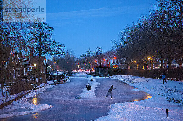 Schlittschuhläuferin allein auf einer Gracht bei Nacht; Amsterdam  Niederlande