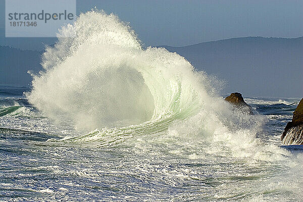 Plätschernde Welle  die sich am Ufer bricht  mit der Küstenlinie von Oregon im Hintergrund am Cape Kiwanda; Oregon  Vereinigte Staaten von Amerika