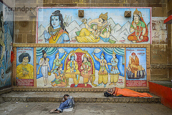 Auf den Ghats schlafende Pilger mit Wandgemälde im Hintergrund; Varanasi  Indien