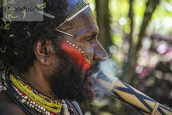 Mitglied des Huli-Stammes beim Rauchen im Tari-Tal im südlichen Hochland von Papua-Neuguinea; Tigibi  südliches Hochland  Papua-Neuguinea