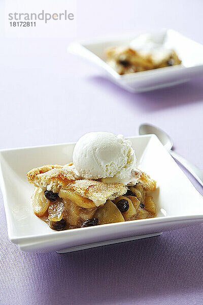 Apfel-Rosinen-Kuchen mit Vanilleeis auf violettem Hintergrund