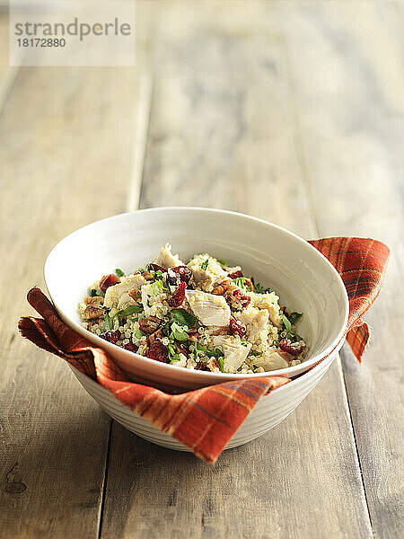 Schüssel mit Orangen-Truthahn-Quinoa  auf Holzhintergrund