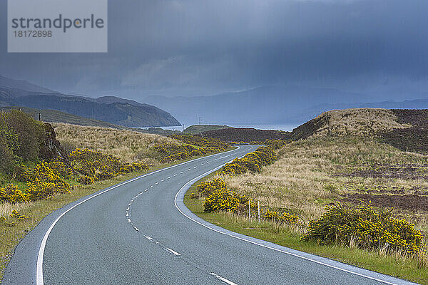 Kurvenreiche Landstraße mit bewölktem Himmel im Frühling auf der Isle of Skye in Schottland  Vereinigtes Königreich