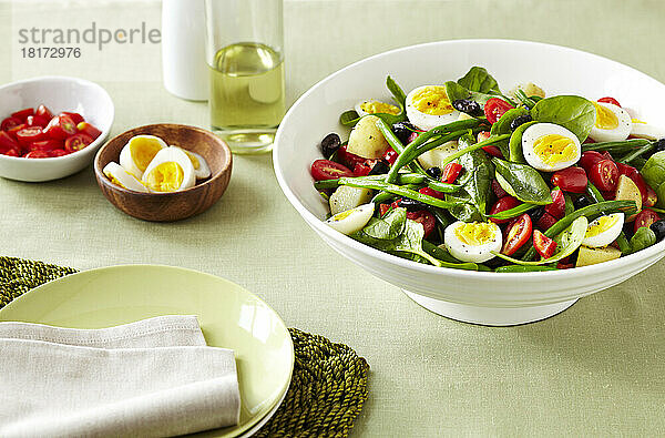 Nicoise-Salat mit Eiern  grünen Bohnen  Tomaten und Oliven auf einer grünen Leinentischdecke