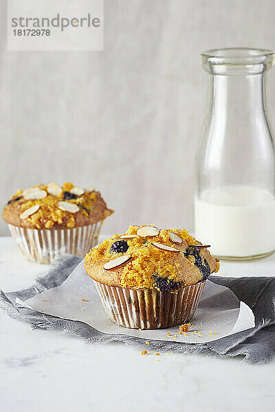 Blaubeer-Mandel-Muffins und eine Flasche Milch im Hintergrund