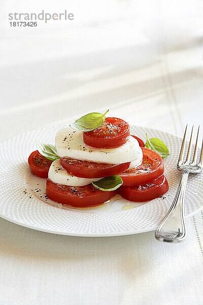 Caprese-Salat auf weißem Teller mit einer Gabel