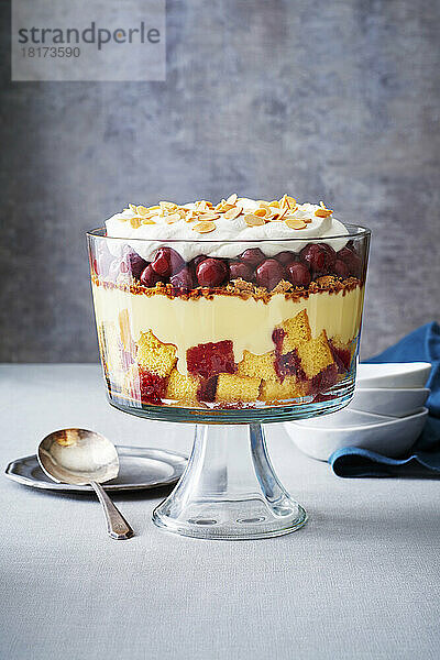 Kirschtrifle in einer Glasschüssel mit Servierlöffel auf grauem Hintergrund