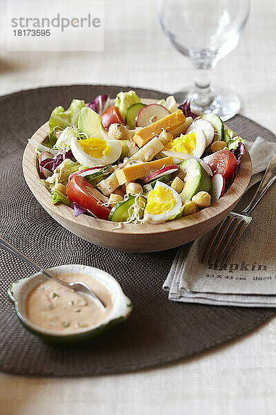 Salat garniert mit Eiern  Kichererbsen  Avocado  Radieschen  Käse und einem cremigen Dressing als Beilage