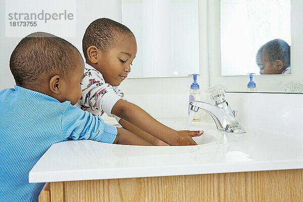 Jungen waschen sich die Hände im Badezimmerwaschbecken