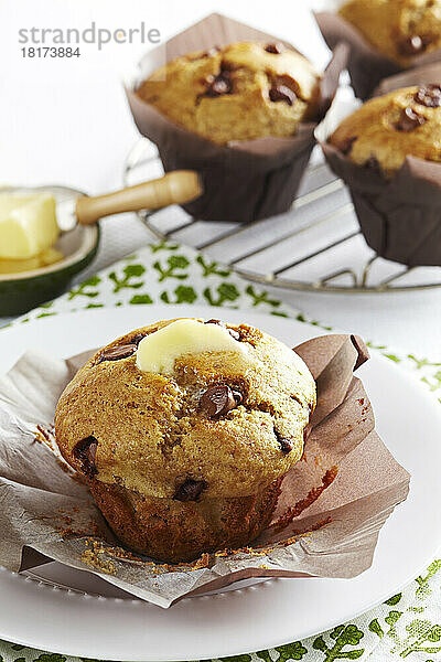 Chocolate-Chip-Muffins mit Butter darauf und einem Kühlregal im Hintergrund