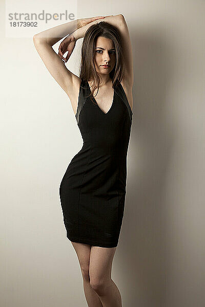 Porträt einer jungen Frau  die ein schwarzes Kleid modelliert  Studioaufnahme