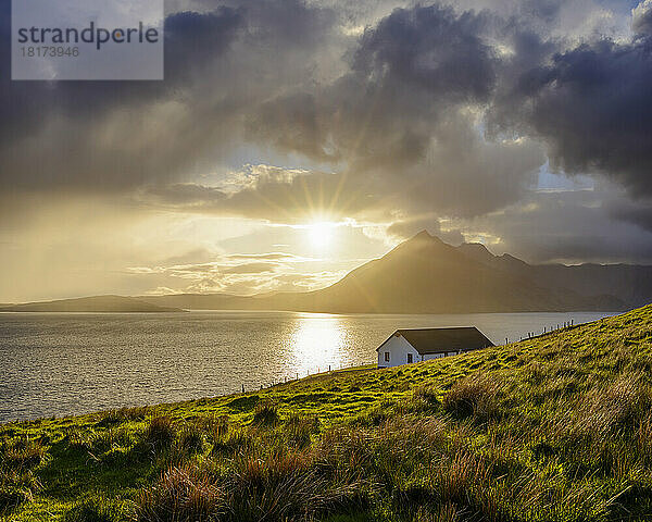 Dach eines Hauses an der schottischen Küste mit Sonne  die durch die dramatischen Wolken über Loch Scavaig auf der Isle of Skye in Schottland  Vereinigtes Königreich  scheint