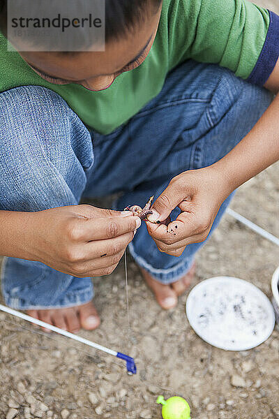 Hockender Junge bereitet Wurm zum Angeln vor  Lake Fairfax  Reston  Virginia  USA