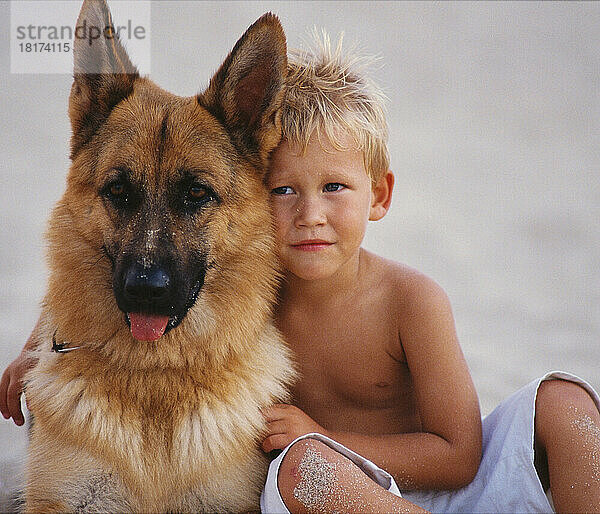Porträt eines Jungen  der einen Hund umarmt