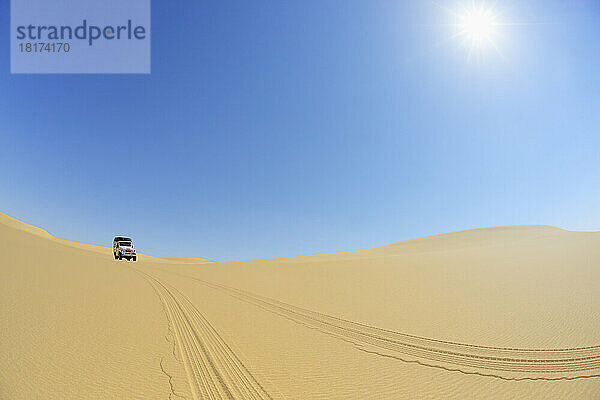 Auto mit Allradantrieb in der Wüste mit blauem Himmel und Sonne  Matruh  Großes Sandmeer  Libysche Wüste  Sahara  Ägypten  Nordafrika  Afrika