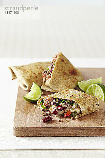 Bohnen-Burrito gefüllt mit Hackfleisch  Paprika und Salat  auf einem Holzbrett