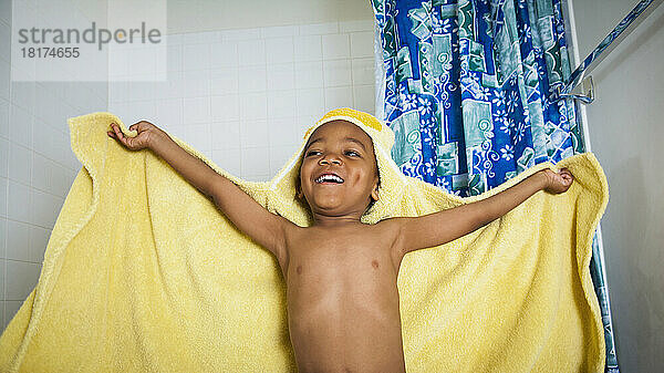 Aufgeregt kommt ein Junge mit einem gelben Kapuzenhandtuch aus dem Bad