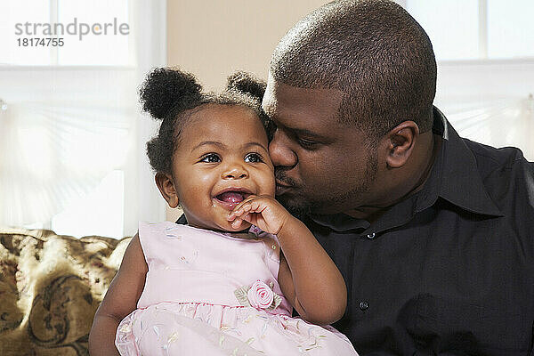 Porträt eines Vaters  der sein kleines Mädchen auf die Wange küsst