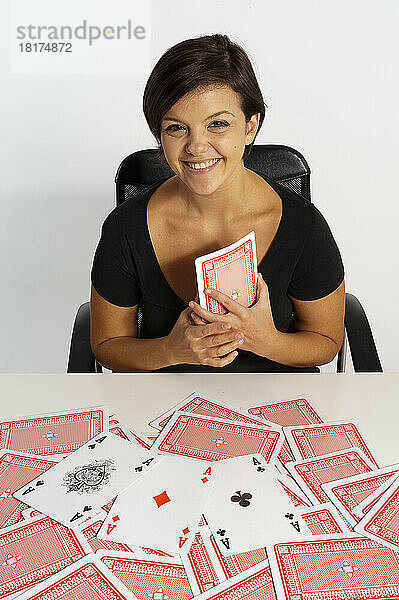 Frau mittleren Alters macht einen Zaubertrick mit einem Kartenspiel