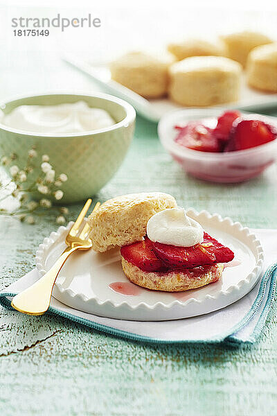 Scones mit Erdbeeren und Schlagsahne auf einem schicken weißen Teller