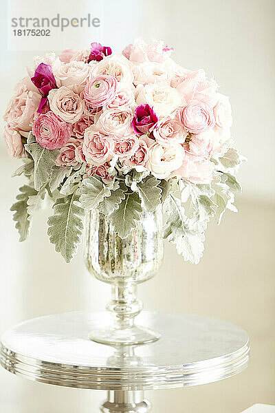 Strauß rosa Rosen in silberner Vase auf silbernem Tisch  Studioaufnahme