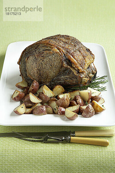 Hochrippen-Roastbeef mit kleinen roten Kartoffeln auf grünem Hintergrund