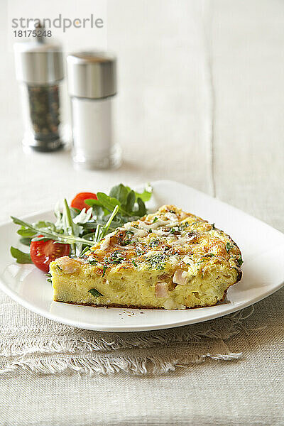 Schinken-Spinca-Frittata mit einfachem Salat auf einem weißen Teller