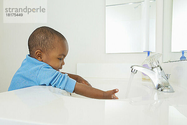 Kleinkind wäscht seine Hände im Badezimmerwaschbecken