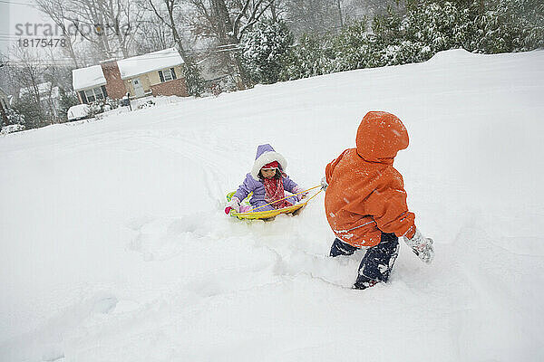 Junge zieht seine kleine Schwester auf Schlitten durch Schnee  Maryland  USA