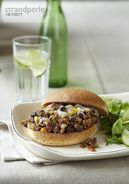 Sloppy Joe auf einem Vollkornbrötchen mit einem Beilagensalat und einem Glas Wasser