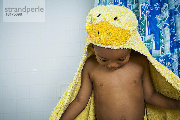 Junge kommt im gelben Entenhandtuch mit Kapuze aus der Badewanne
