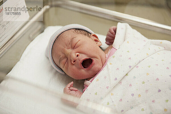 Newborn Baby Girl Yawning in Hospital Bassinet