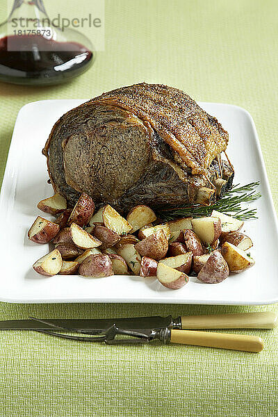 Hochrippen-Roastbeef mit kleinen roten Kartoffeln und Rotwein auf grünem Hintergrund