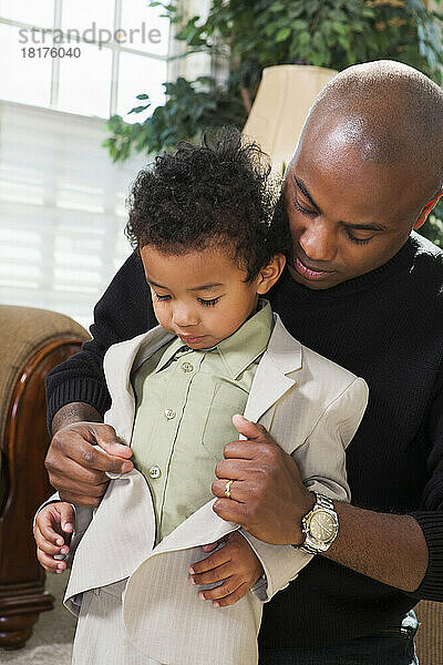 Vater hilft seinem Sohn  die Anzugjacke zuzuknöpfen  und bereitet sich auf die Kirche vor