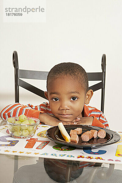 Junge unzufrieden mit seinem Mittagessen am Küchentisch
