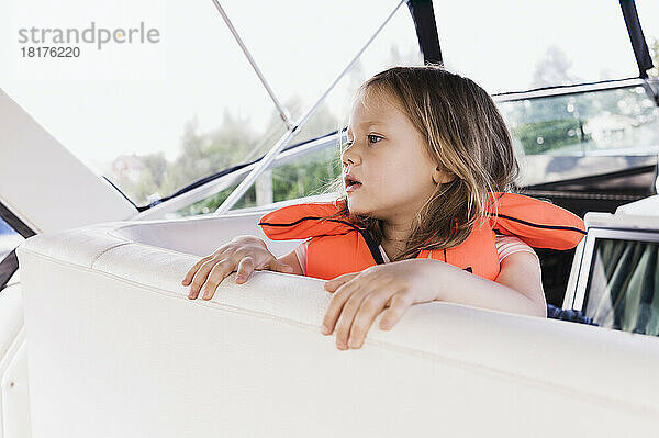 Nahaufnahme eines 3-jährigen Mädchens in orangefarbener Schwimmweste auf einem Motorboot  Schweden