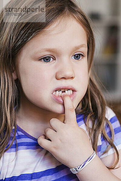 Nahaufnahme eines Mädchens  das Platz für ihren fehlenden Zahn berührt