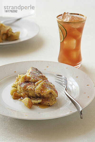 Apfelbrotpudding und Ahornsirup mit einem Glas tropischem Fruchtsaft