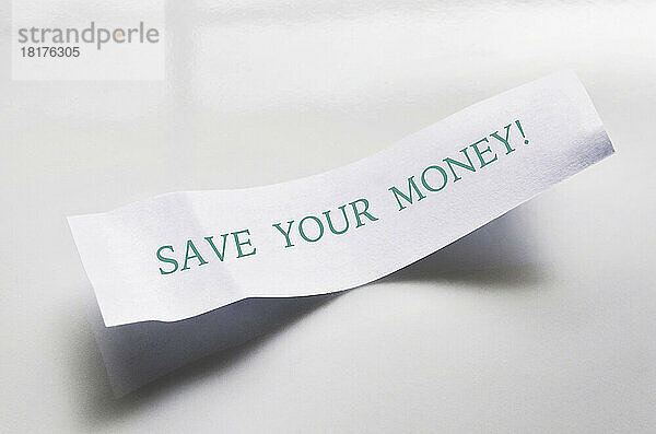 Nahaufnahme der Nachricht vom Glückskeks auf weißem Teller  mit Text zum Geldsparen  Studioaufnahme auf weißem Hintergrund