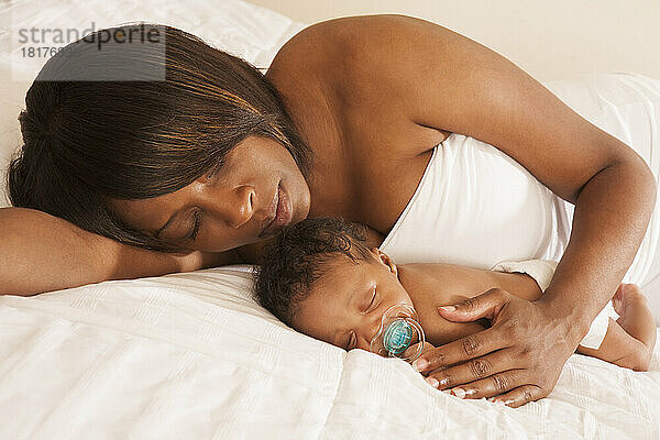 Mutter liegt mit schlafendem Neugeborenen