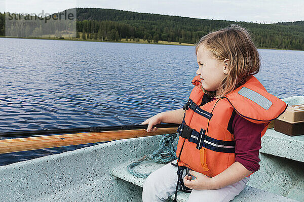 3 Jahre altes Mädchen in orangefarbener Schwimmweste sitzt in einem Motorboot  Angeln  Schweden