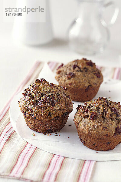 Cranberry-Leinsamen-Muffins auf einem weißen Teller mit einer gestreiften Serviette