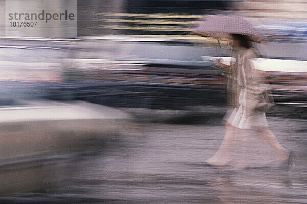 Verschwommene Sicht auf eine Frau  die im Regen spaziert  Paris  Frankreich