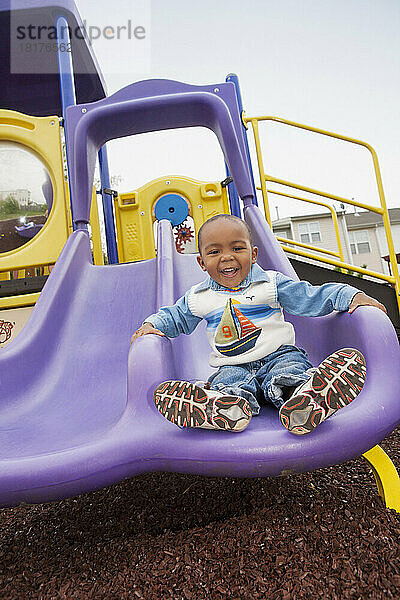 Porträt eines Jungen  der auf einer Spielplatzrutsche spielt  Maryland  USA