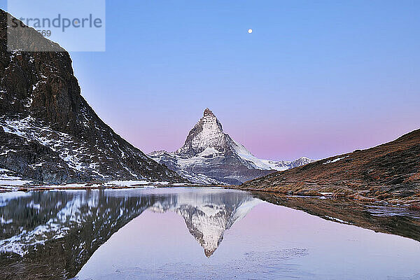 Matterhorn spiegelt sich im Riffelsee im Morgengrauen mit Mond  Zermatt  Alpen  Wallis  Schweiz
